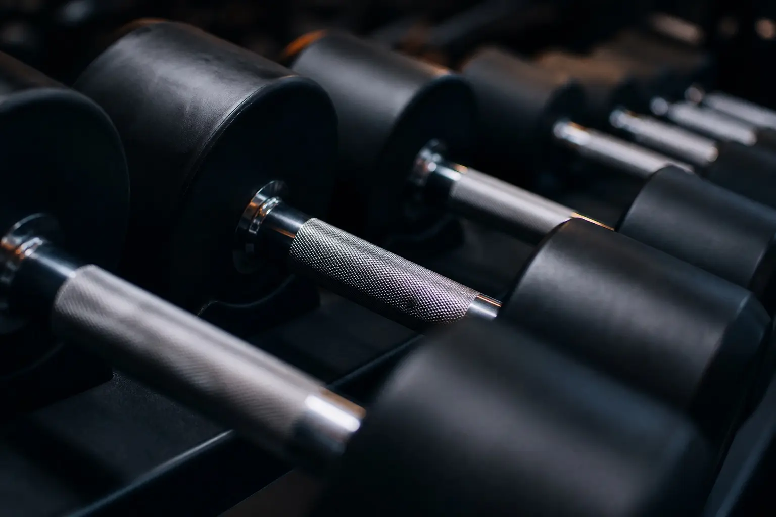 Black rubber dumbbells with chrome handles on a rack